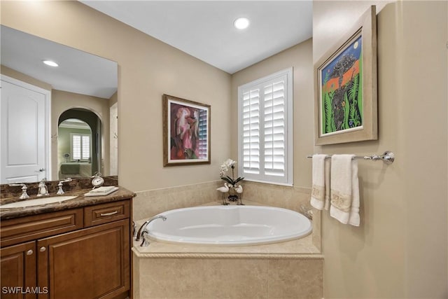 bathroom with vanity, a bath, and recessed lighting