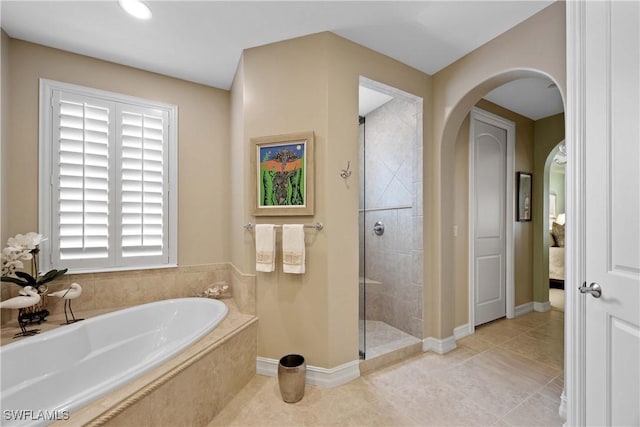 ensuite bathroom with tile patterned floors, ensuite bathroom, a shower stall, baseboards, and a bath