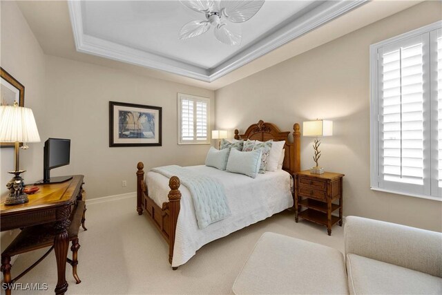 bedroom featuring a tray ceiling, light colored carpet, crown molding, and baseboards