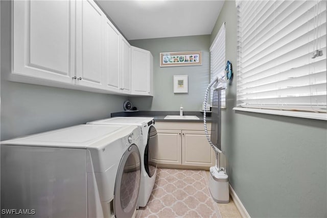 clothes washing area with washing machine and dryer, a sink, cabinet space, and baseboards