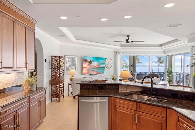 kitchen featuring a tray ceiling, open floor plan, a sink, and stainless steel dishwasher