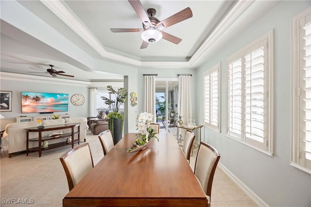 dining room with a tray ceiling, plenty of natural light, light tile patterned flooring, and crown molding