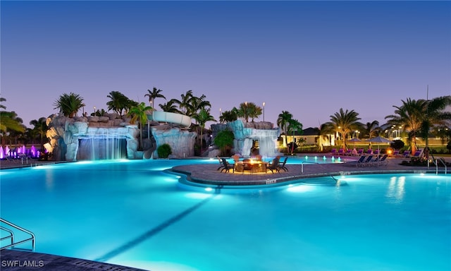 pool at dusk with pool water feature and a patio area