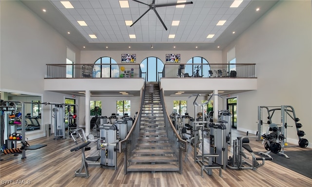 gym with wood-type flooring, a towering ceiling, and a paneled ceiling