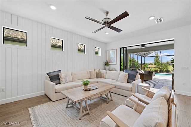 living room with wood walls, ceiling fan, and hardwood / wood-style flooring