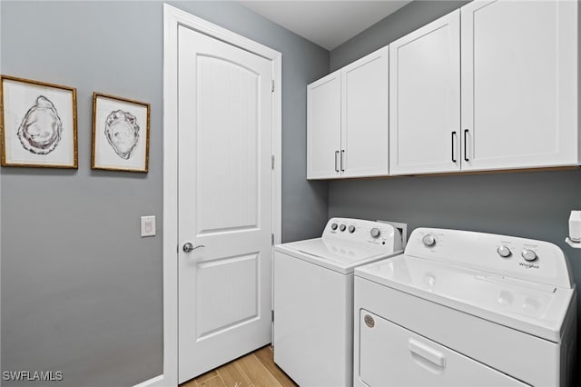 clothes washing area featuring light hardwood / wood-style floors, washing machine and dryer, and cabinets