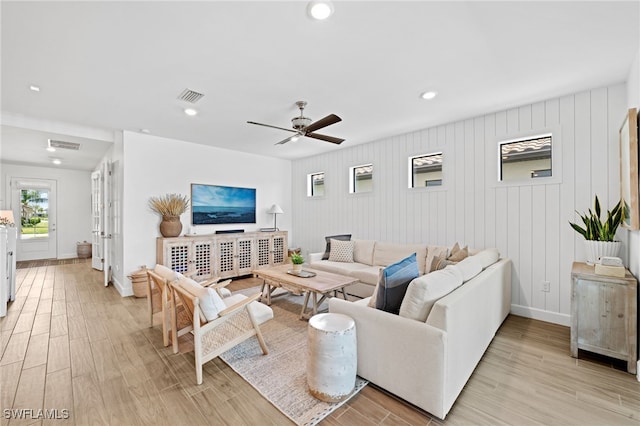 living room featuring wooden walls, ceiling fan, and light hardwood / wood-style flooring