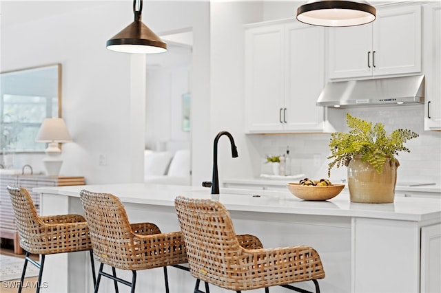 kitchen with a kitchen breakfast bar, white cabinets, tasteful backsplash, and extractor fan