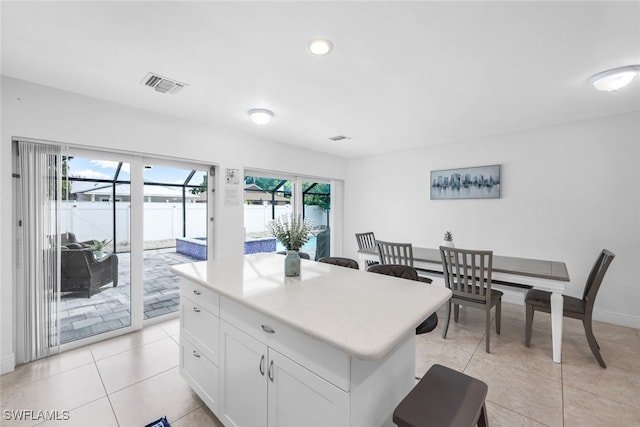 kitchen with a center island, white cabinetry, a wealth of natural light, and light tile patterned flooring