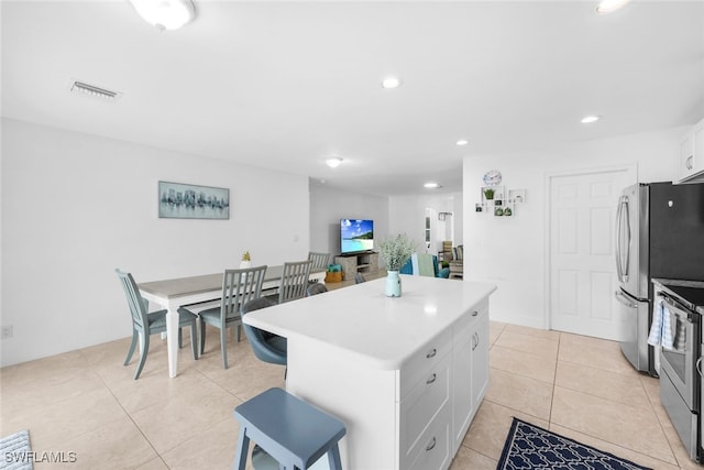 kitchen featuring white cabinets, appliances with stainless steel finishes, a center island, and light tile patterned flooring