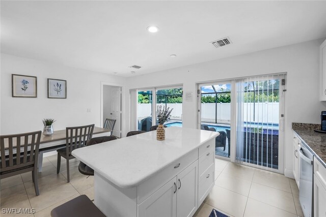 kitchen with dishwasher, white cabinetry, a kitchen island, and a healthy amount of sunlight