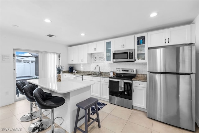 kitchen featuring a center island, a kitchen breakfast bar, tasteful backsplash, white cabinetry, and stainless steel appliances