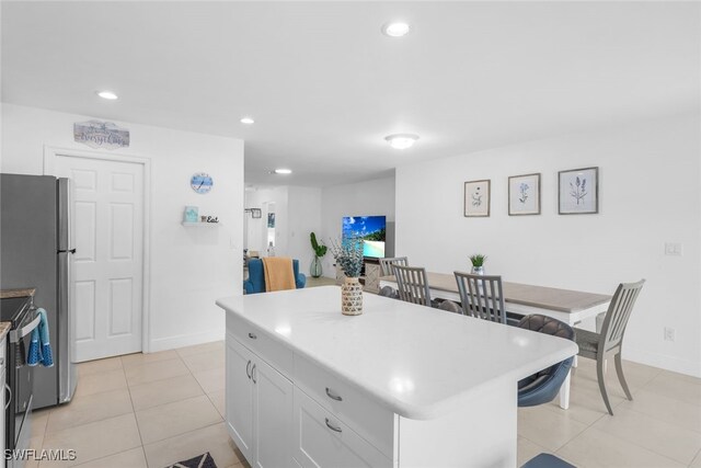 kitchen with appliances with stainless steel finishes, a center island, white cabinetry, and light tile patterned floors