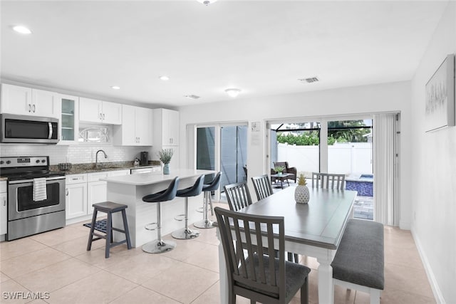 kitchen featuring decorative backsplash, appliances with stainless steel finishes, white cabinets, and light tile patterned flooring