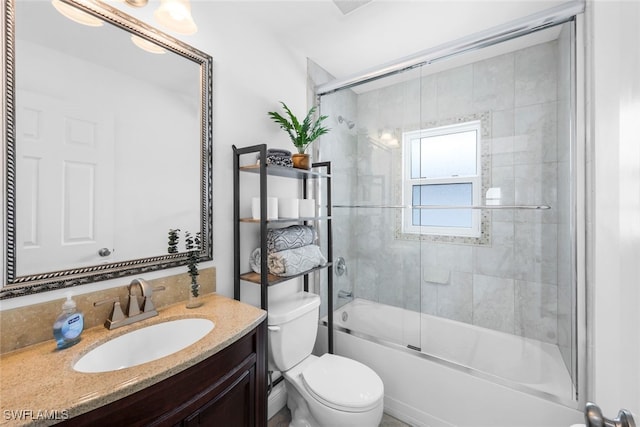 full bathroom featuring vanity, toilet, and bath / shower combo with glass door