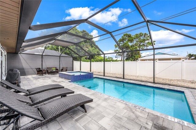 view of swimming pool featuring a lanai, a patio area, and an in ground hot tub