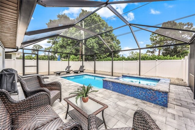 view of pool featuring an in ground hot tub, area for grilling, a patio, and glass enclosure