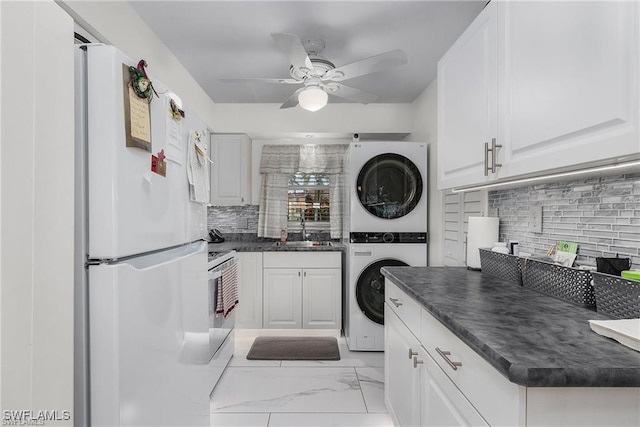 kitchen with sink, stacked washing maching and dryer, white appliances, decorative backsplash, and white cabinets