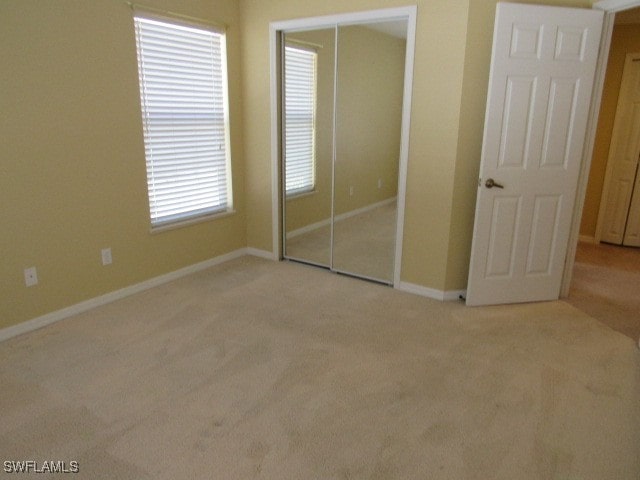 unfurnished bedroom with light carpet and a closet