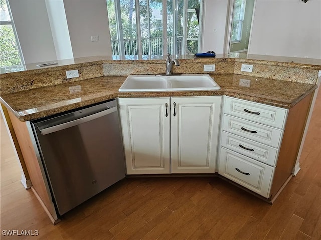 kitchen with light wood-type flooring, white cabinets, stainless steel dishwasher, and sink