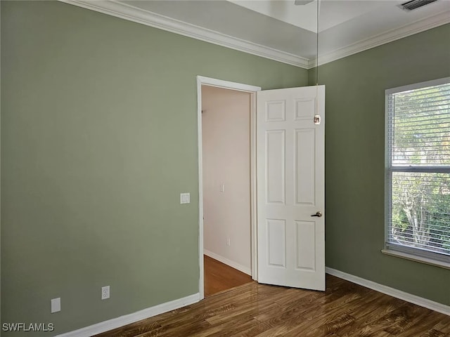 empty room with dark hardwood / wood-style flooring, crown molding, and a healthy amount of sunlight