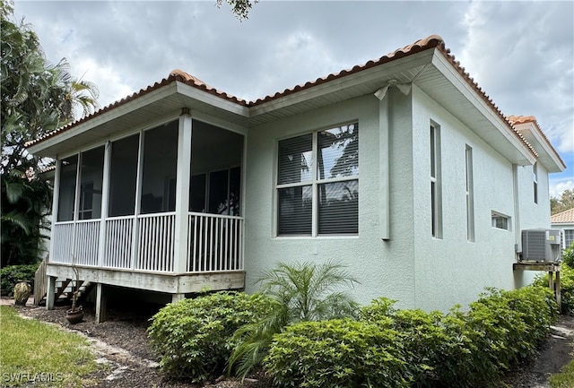 view of home's exterior with central AC unit and a sunroom