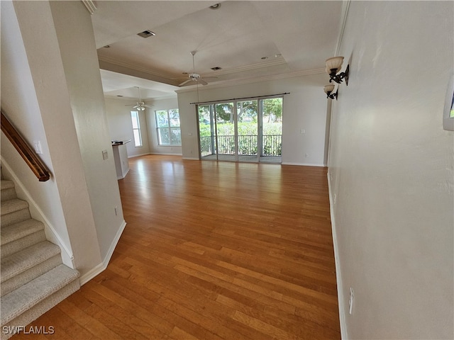 spare room featuring light wood-type flooring, a raised ceiling, ornamental molding, and ceiling fan