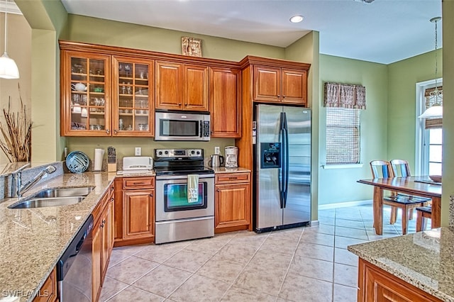 kitchen featuring pendant lighting, light tile patterned floors, sink, light stone countertops, and appliances with stainless steel finishes