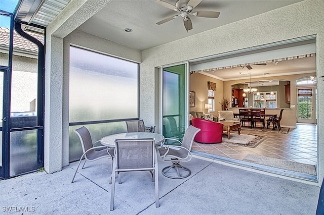 sunroom featuring ceiling fan with notable chandelier