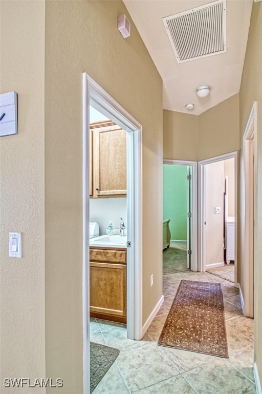 hall with sink and light tile patterned flooring