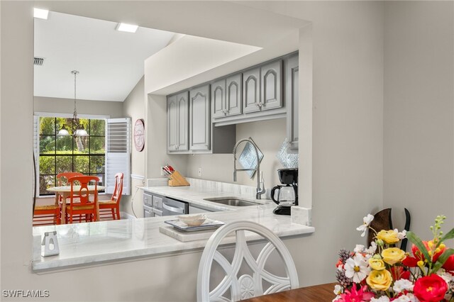 kitchen featuring hanging light fixtures, gray cabinetry, light stone countertops, stainless steel dishwasher, and sink