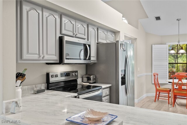 kitchen featuring an inviting chandelier, light hardwood / wood-style flooring, stainless steel appliances, gray cabinets, and hanging light fixtures