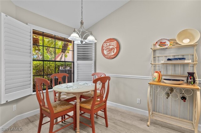 dining room with light wood-type flooring, lofted ceiling, and a chandelier