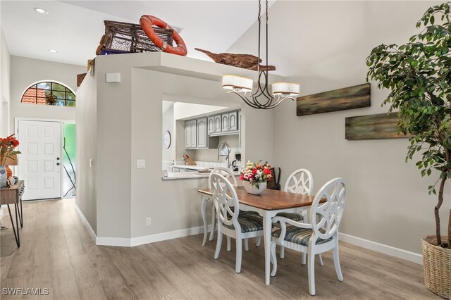 dining area with light wood-type flooring and a notable chandelier