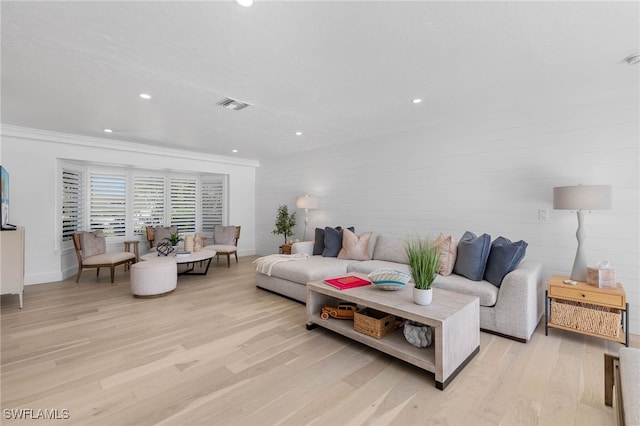 living room featuring crown molding and light hardwood / wood-style flooring