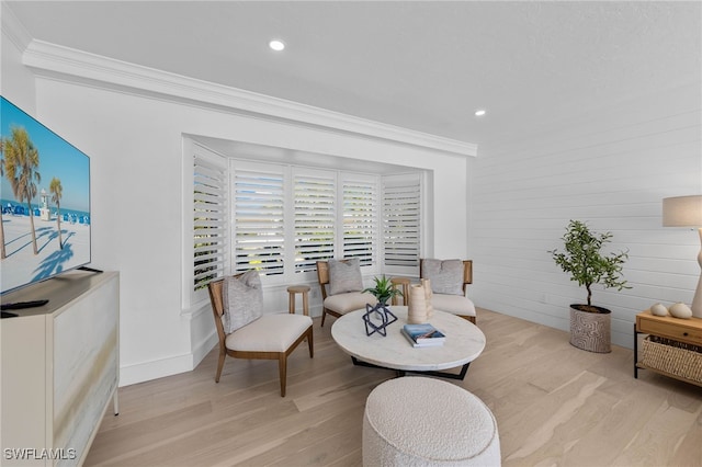 living area featuring ornamental molding and light hardwood / wood-style floors