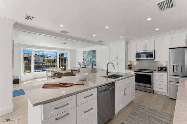 kitchen featuring a kitchen island with sink, light hardwood / wood-style flooring, sink, white cabinets, and appliances with stainless steel finishes