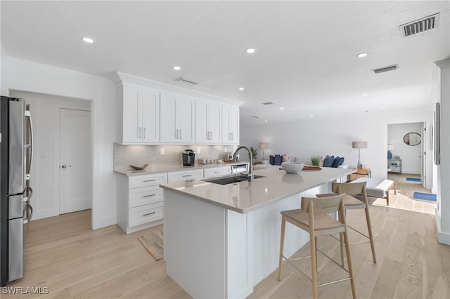 kitchen featuring sink, white cabinets, light hardwood / wood-style flooring, and stainless steel refrigerator