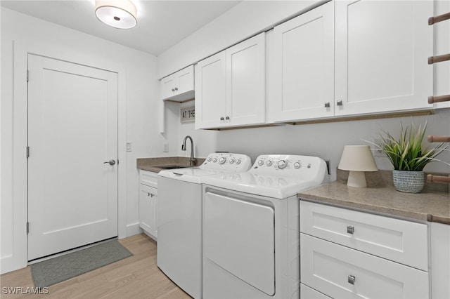 laundry room with light hardwood / wood-style floors, independent washer and dryer, sink, and cabinets