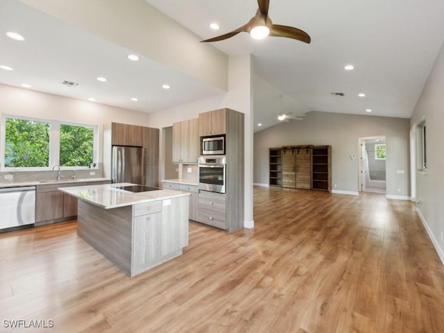 kitchen with light stone counters, stainless steel appliances, a wealth of natural light, a kitchen island, and modern cabinets