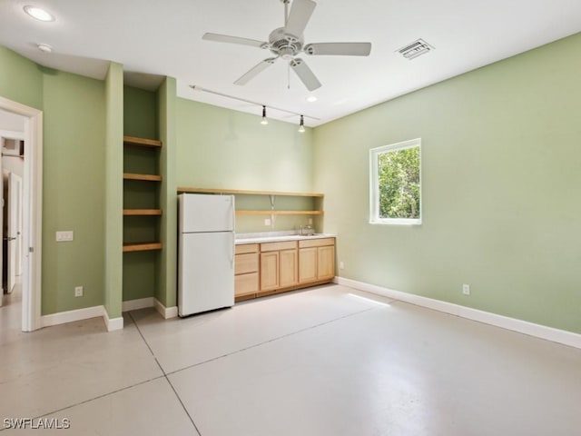 kitchen with concrete floors, visible vents, baseboards, freestanding refrigerator, and light brown cabinetry