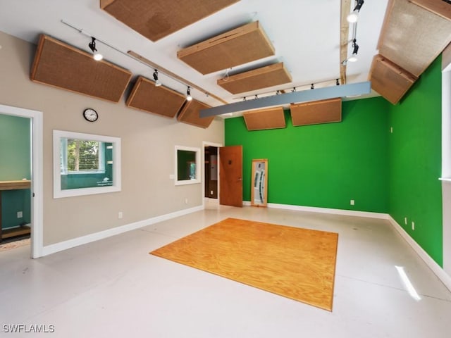 interior space with baseboards, finished concrete flooring, and track lighting