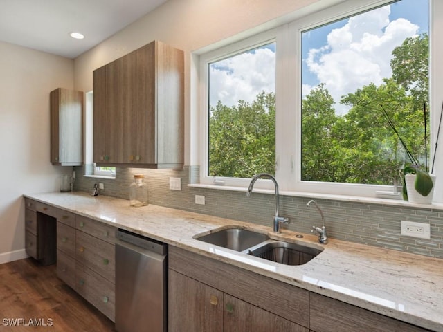 kitchen featuring dishwasher, light stone counters, dark wood-style flooring, a sink, and backsplash