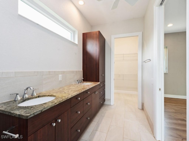 bathroom with double vanity, a sink, a ceiling fan, and baseboards