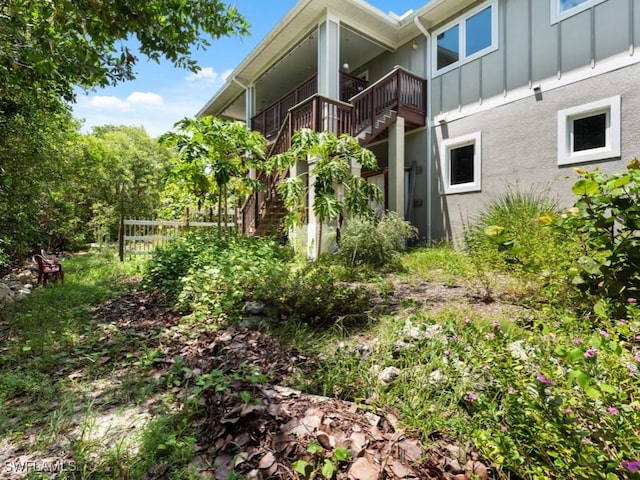 view of home's exterior with stairway, board and batten siding, fence, and stucco siding