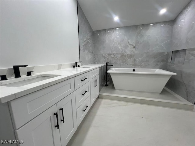 bathroom featuring a washtub, vanity, and tile walls