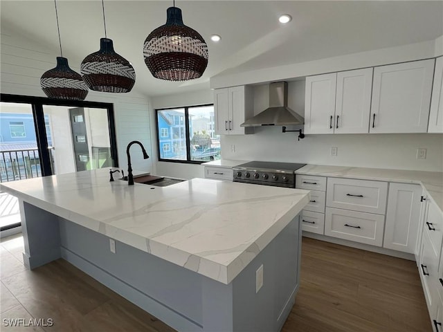 kitchen with sink, hanging light fixtures, wall chimney range hood, vaulted ceiling, and white cabinets