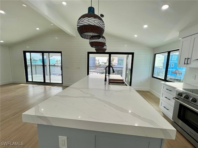 kitchen with light stone countertops, a kitchen island with sink, sink, pendant lighting, and stainless steel electric range oven