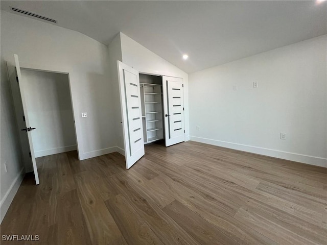 unfurnished bedroom with hardwood / wood-style floors and vaulted ceiling