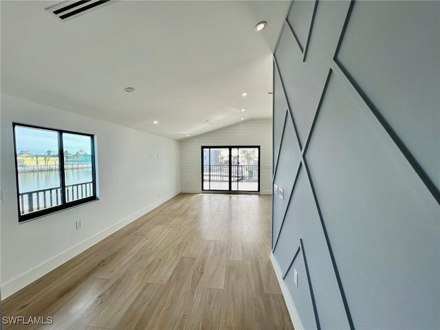 unfurnished room with a water view, light hardwood / wood-style floors, and lofted ceiling